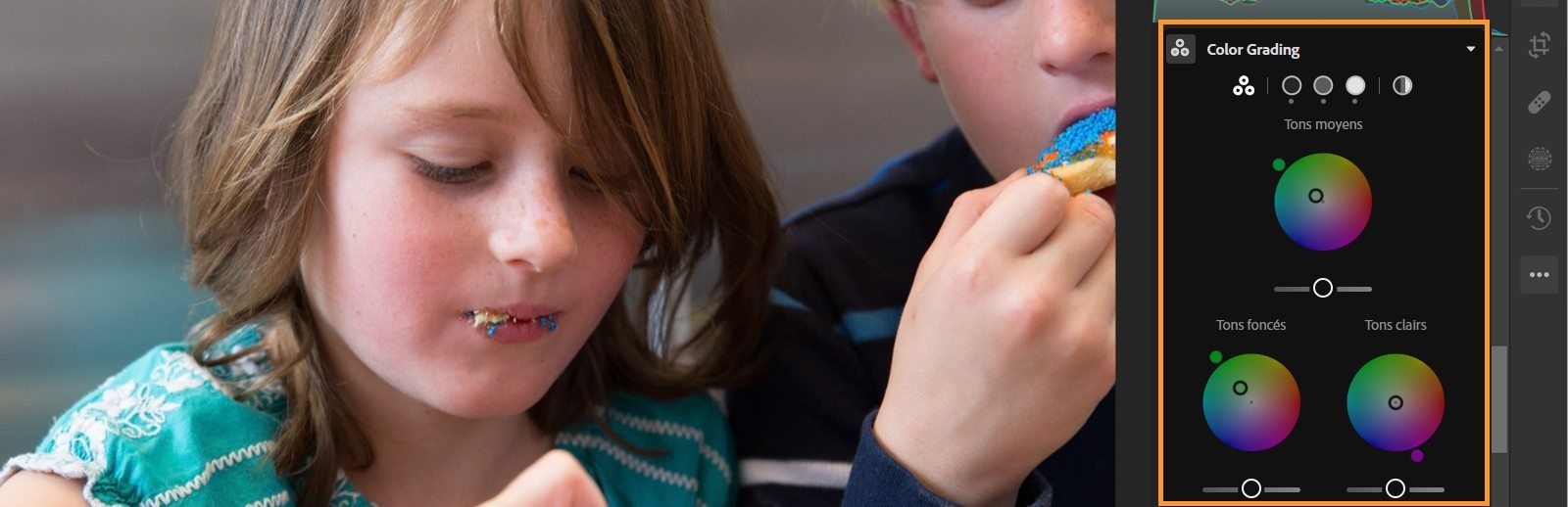 L’image de deux enfants apparaît avec le panneau Color Grading mis en surbrillance dans le panneau Modifier. Trois curseurs pour les tons moyens, les ombres et les hautes lumières sont définis.